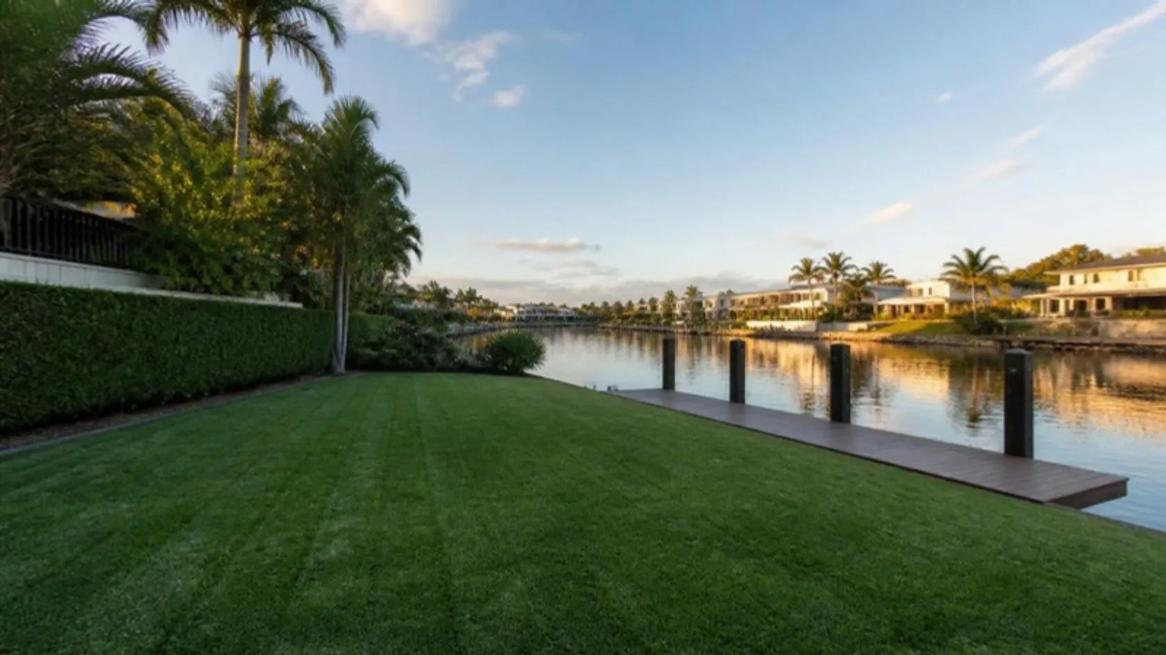 Mown canal-front lawn with a pontoon