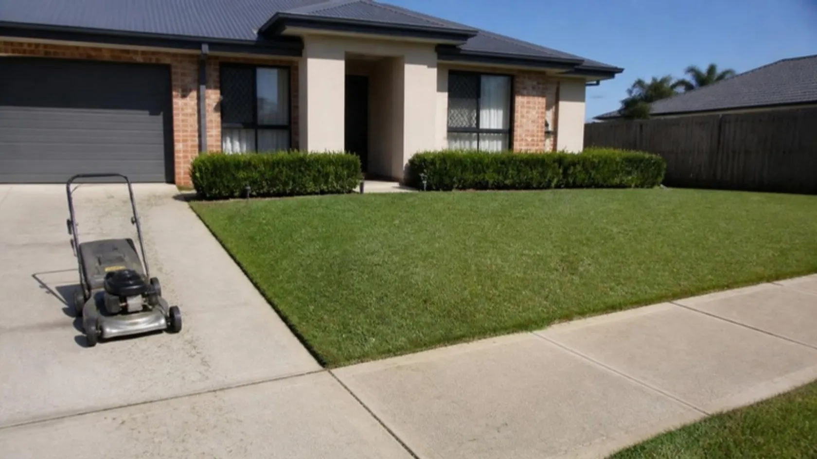 Freshly mown front lawn with a push mower on the driveway