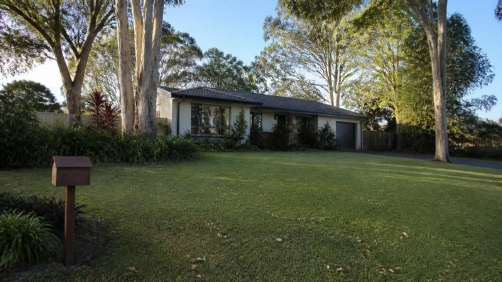 Big mown front lawn on a leafy block with gum trees