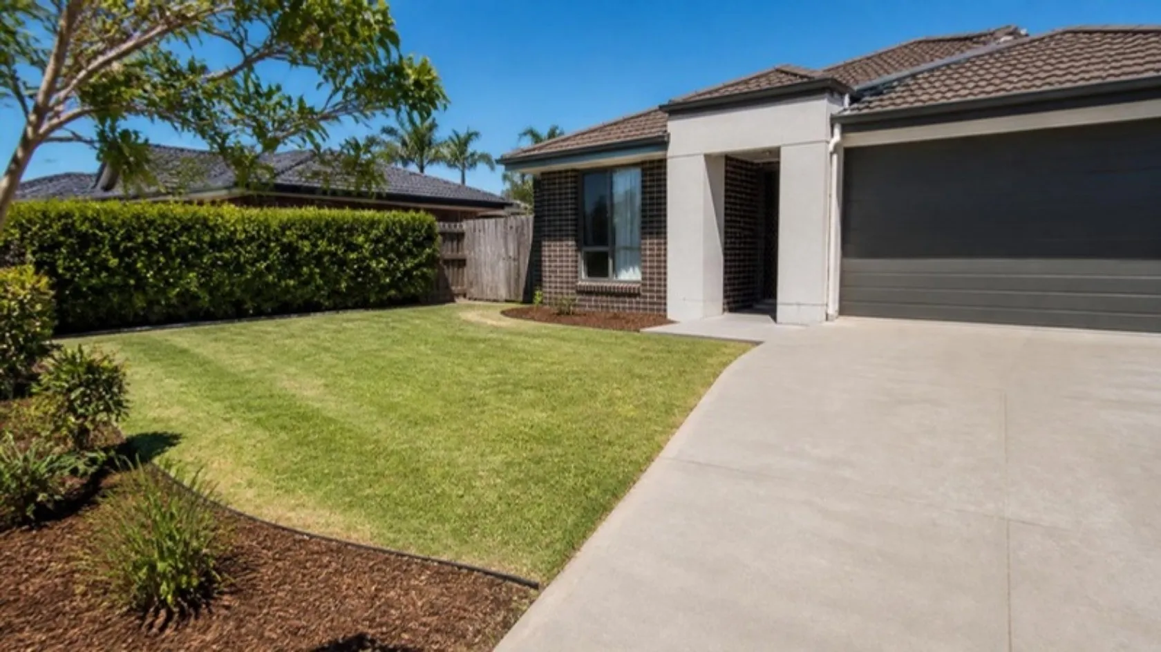 Front yard with mown lawn, trimmed hedge and fresh mulch